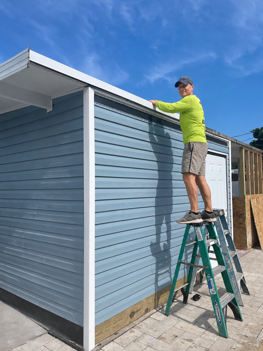 Exterior siding and white corner trim being installed on a blue building