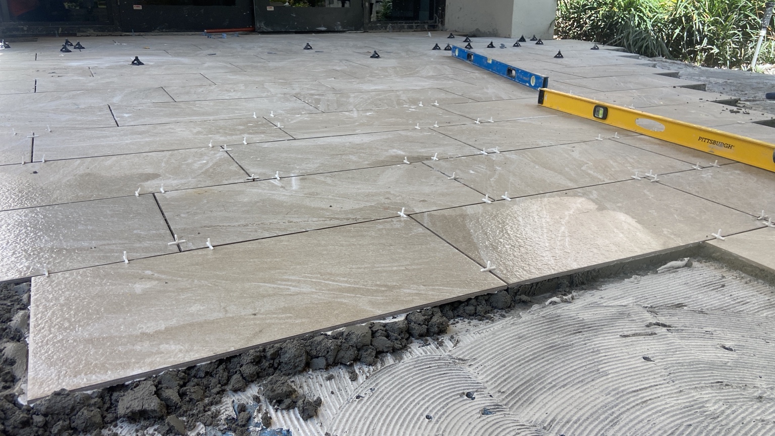 Large-format tile installation in progress, with spacers and levels